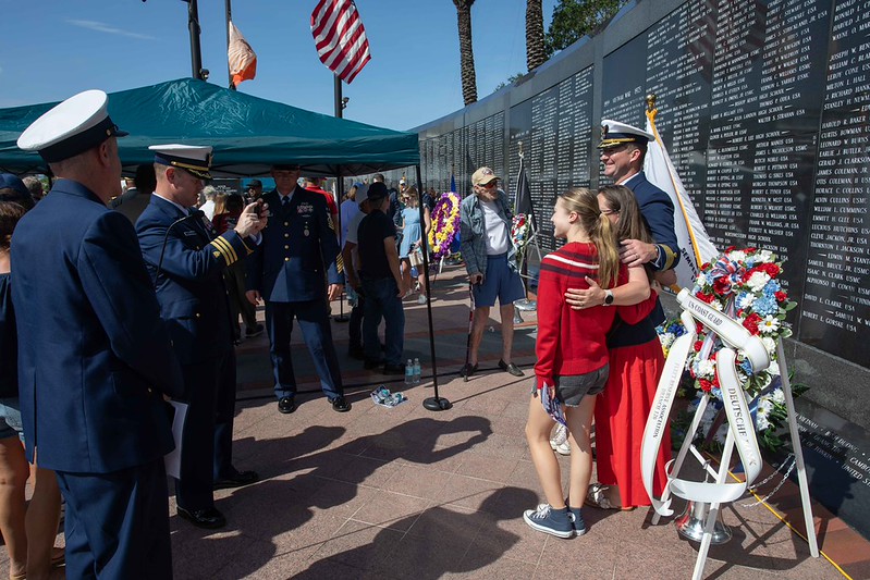 people taking photos at Memorial Day 2026 service with Memorial Wall in background