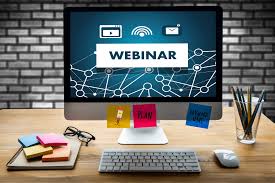 Computer monitor with word webinar and some sticky notes, keyboard and mouse on top of the desk
