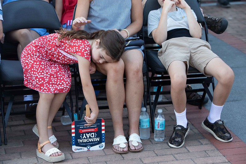 A child sleeping on lap of person at Memorial Day 2026 service
