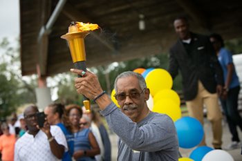 Man in crowd holding torch for senior games