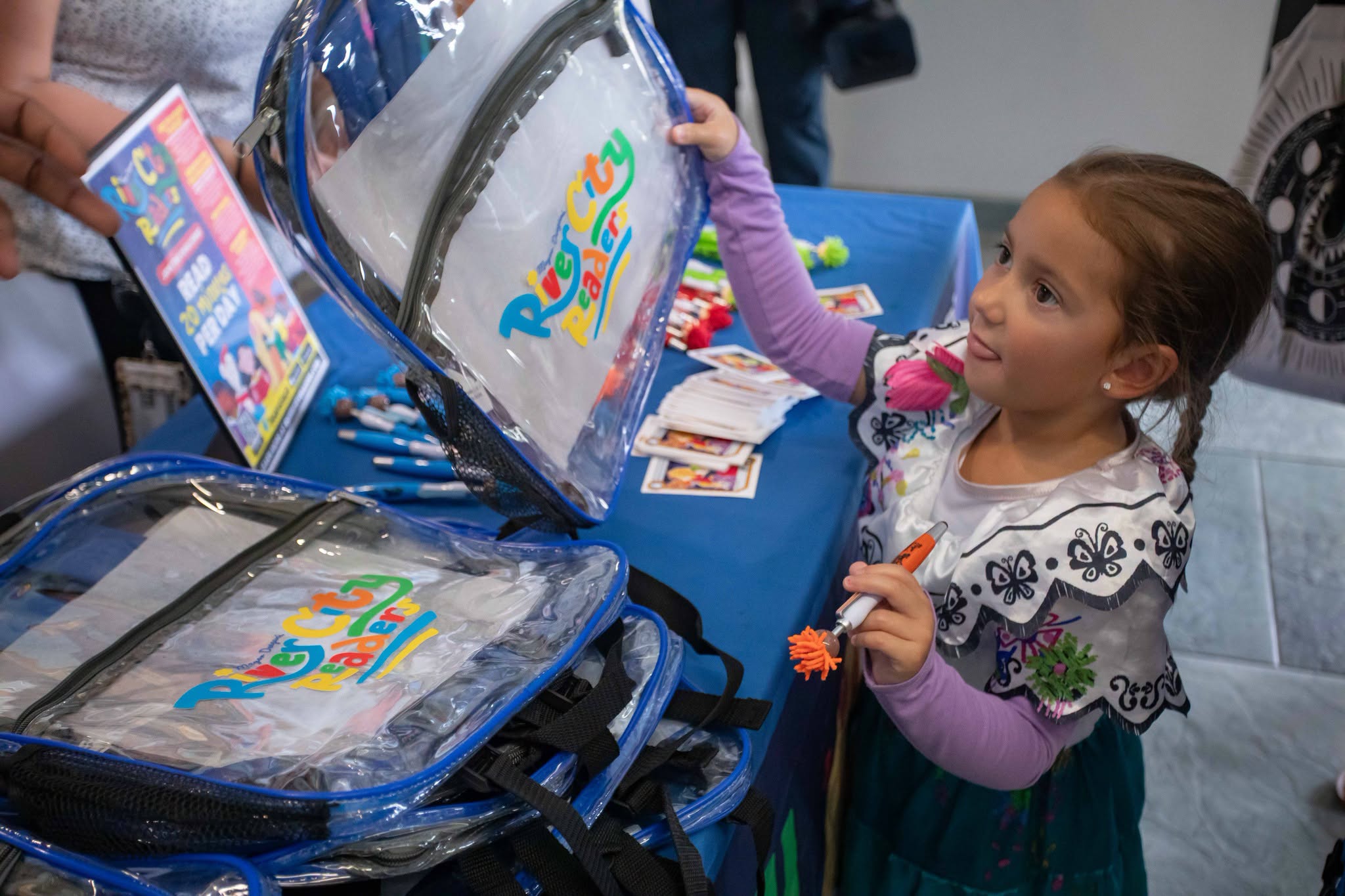 Child reaching for backpack at river city readers event