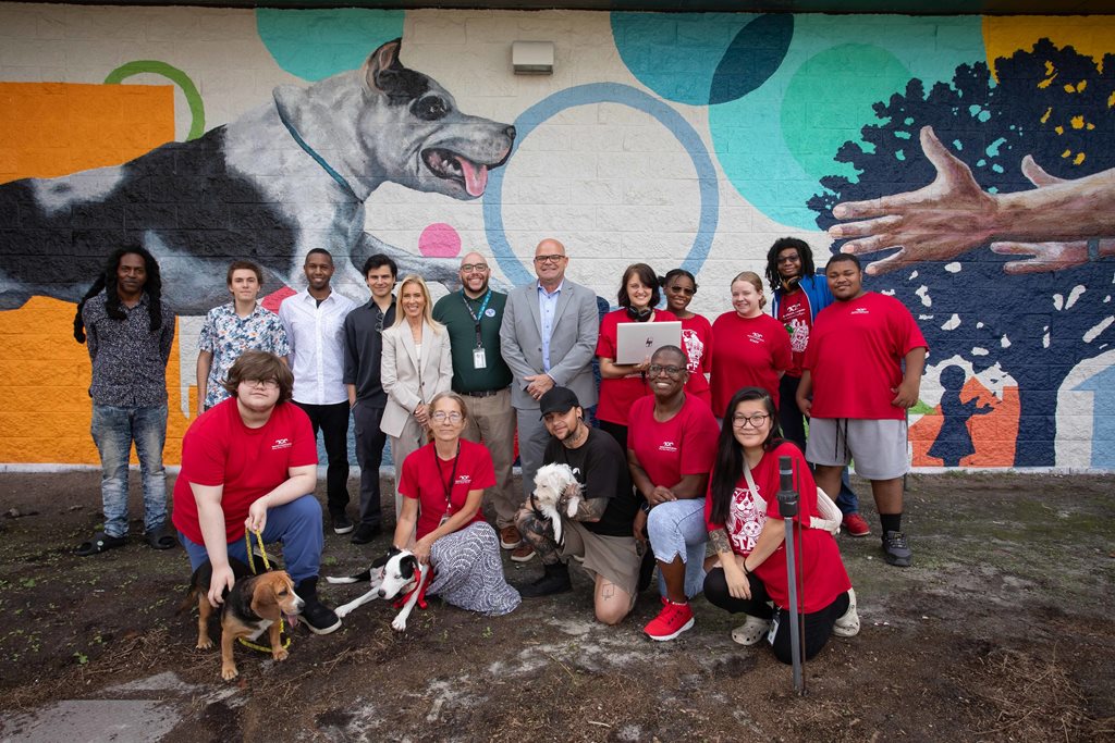 group photo of people and dogs in front of ACPS pets mural