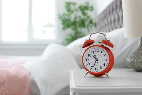 Red alarm clock next to a bed Red alarm clock next to a bed