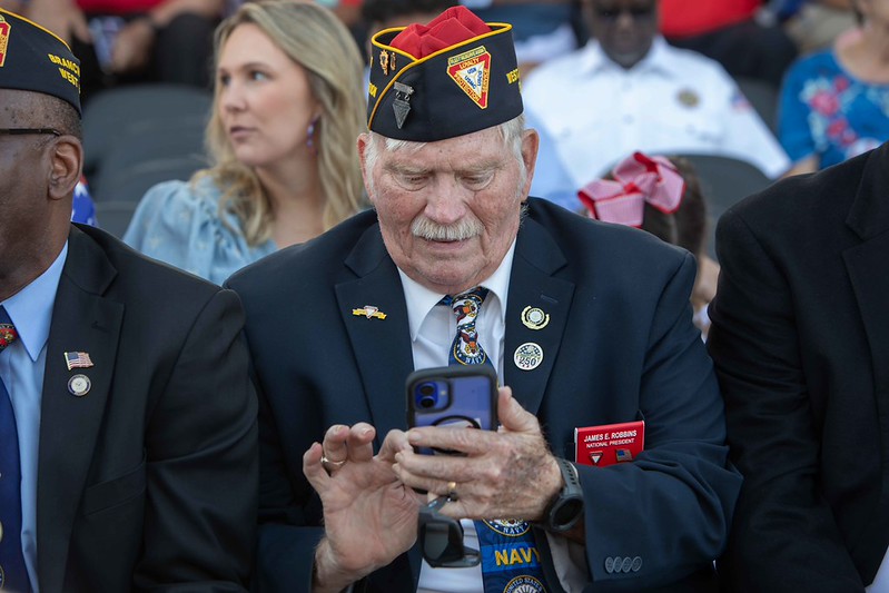 A man looking at his phone at Memorial Day 2026 service