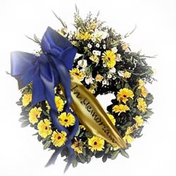 A photo of a wreath with a bow and flowers with a message on a ribbon reading "In Memoriam".