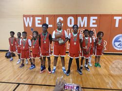 A picture of a youth boys basketball team. Children ranging from the ages of 5 to 17 standing with championship medals.