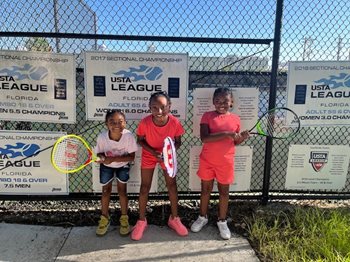 Three kids with tennis rackets smiling