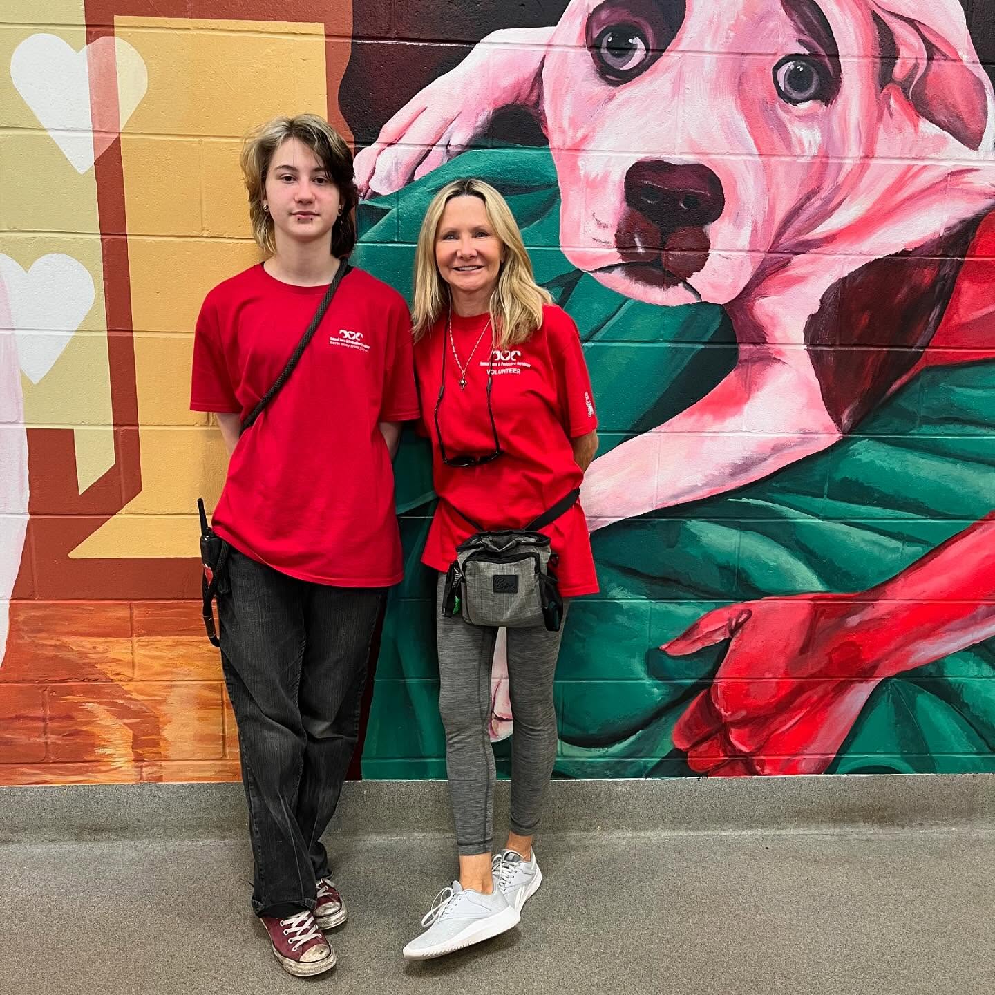 Two people in red shirts standing in front of colorful background