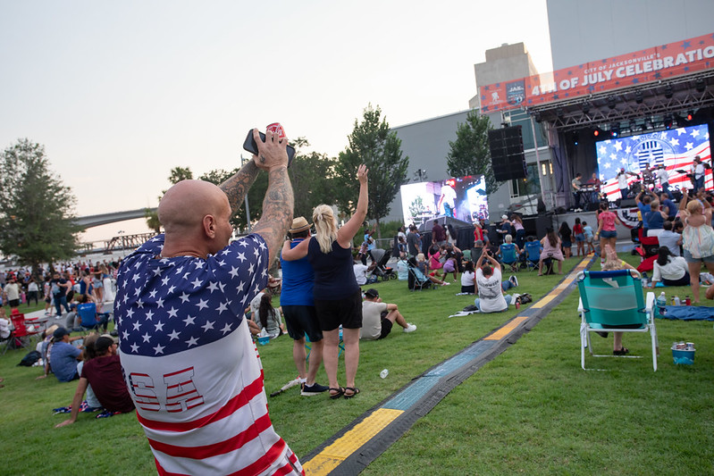 A man with patriotic shirt listening and reacting to the live music at the July 4th celebration 