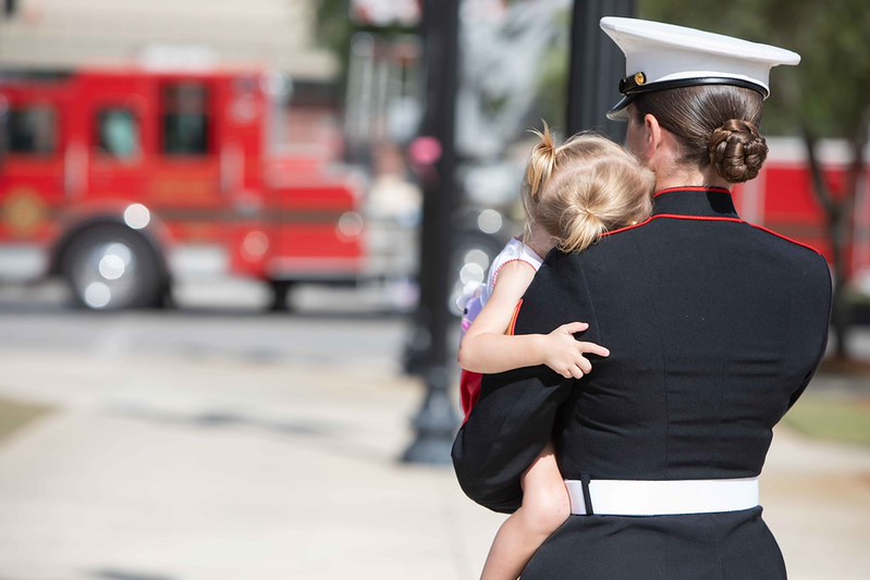 A Marine carrying her small child at Memorial Day 2026 service