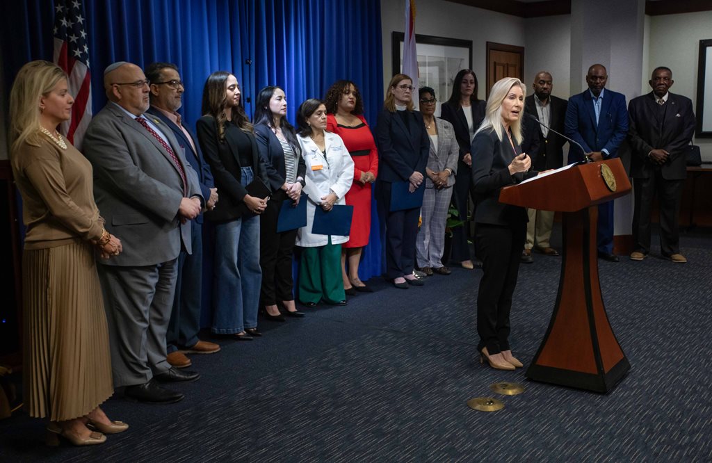 Mayor standing at podium with line of men and women standing behind her