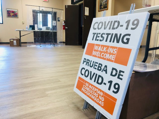 A CODIV-19 Testing Site sign leaning against a desk