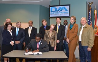Mayor Brown surrounded by members of the Downtown Investment Authority, signing Ordinance 2014-560 into law