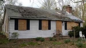 Picture of an old, dilapidated house with boarded up windows and unkempt yard