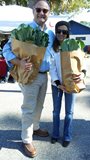 man and woman holding paper bags full of collard greens