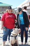 2 women standing on beach with dog