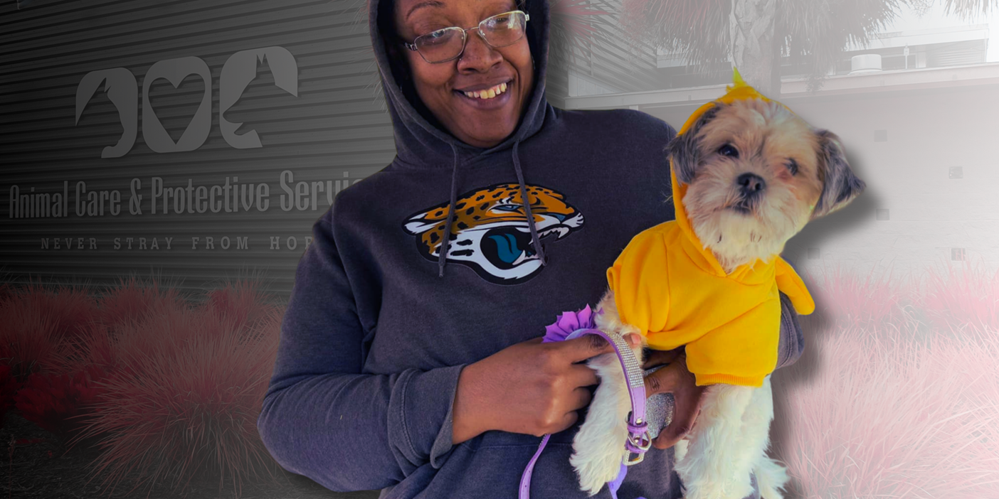 woman holding dog in front of ACPS building.