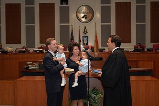 Photo of Council President Clay Yarborough taking the Oath of Office admnistered by Judge Adrian Soud, while his wife, Jordan Yarborough and twin sons look on.