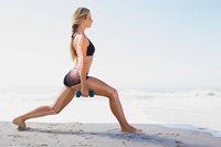 Woman at the beach, holding dumbell for strong bones