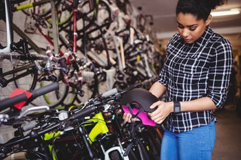 woman in a bike shop selecting a helmet