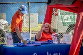 booth employees at the family health and fitness day waving at the camera