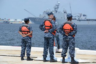 Photo of marines standing on the dock awaiting the arrival of the USS Iwo Jima.