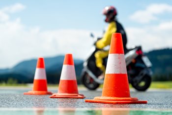 man on motocycle driving between cones at safety clas