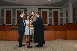 Photo of Council Vice President Greg Anderson taking the Oath of Office administered by Judge Gary Flower, while his wife Beville Anderson looks on.