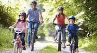 Family of four riding a bicycle trees as background