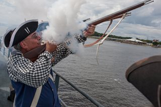 Photo of the Sons of the Revolutionary War firing muskets in a gun salute.