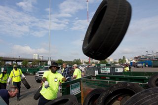 Photo of a worker tossing a waste tire into a disposal roll-off container.